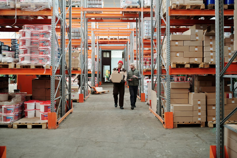 Magazijnmedewerkers lopen tussen pallets met verzenddozen - fulfillment en pooling