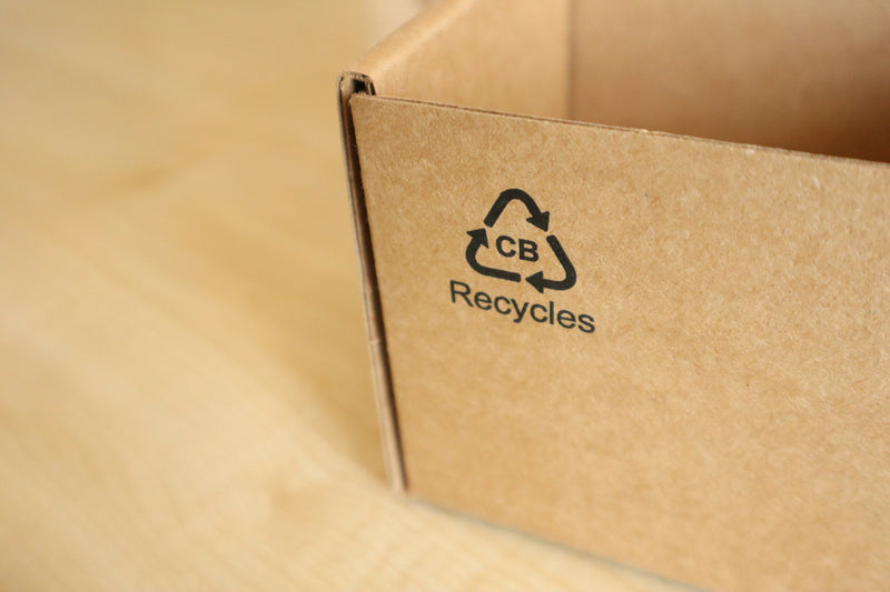 Kartonnen doos met recycle-logo — herbruikbaar vs recyclebaar